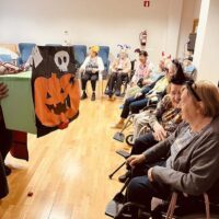 Varias personas mayores en una sala decoarada con motivos de Halloween